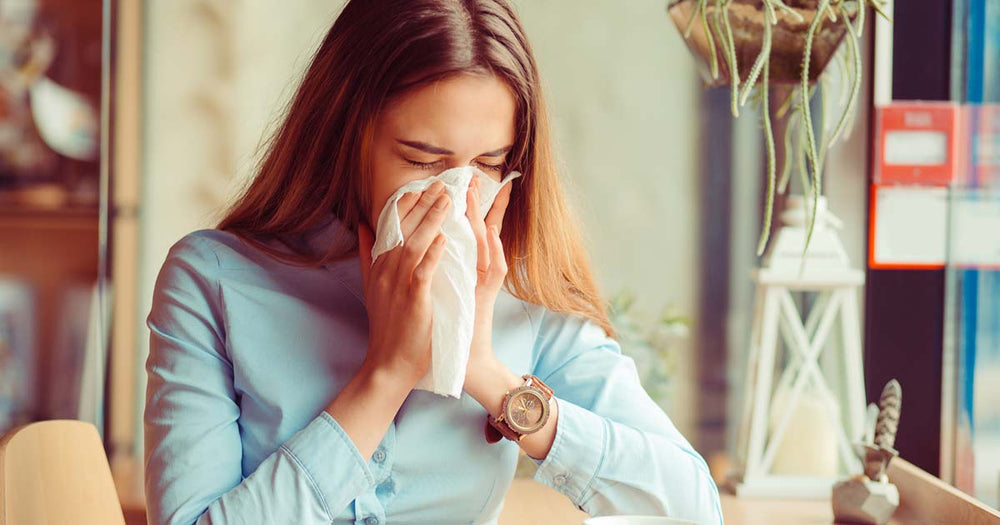 A woman blowing her nose into a a tissue