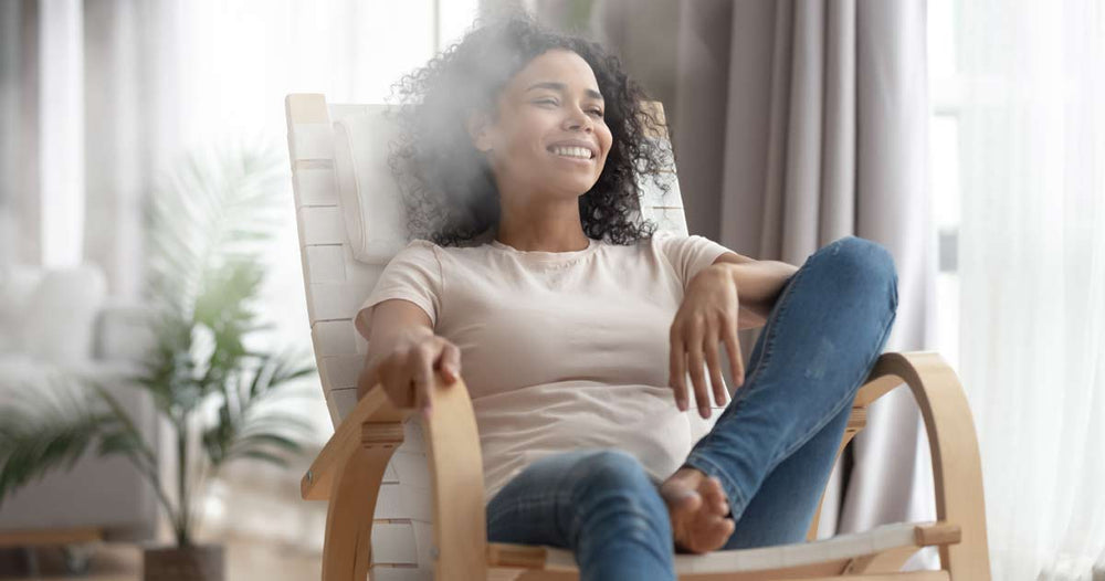 Woman sitting in a chair beside a plume of mist coming from a humidifer