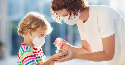 Mother squeezing hand sanitizer on son's hands