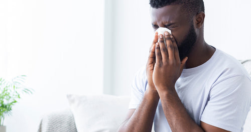 A man suffering from allergies that could be reduced with a quality air purifier