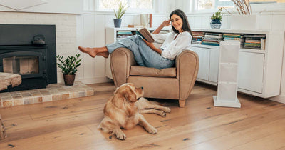 Woman reading a book in her living room with her dog beside her