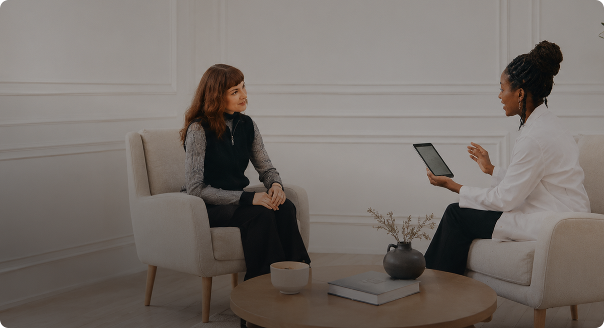 Two women talking in a living room while looking at a tablet
