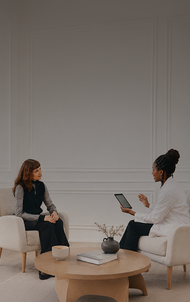 Two women talking in a living room while looking at a tablet