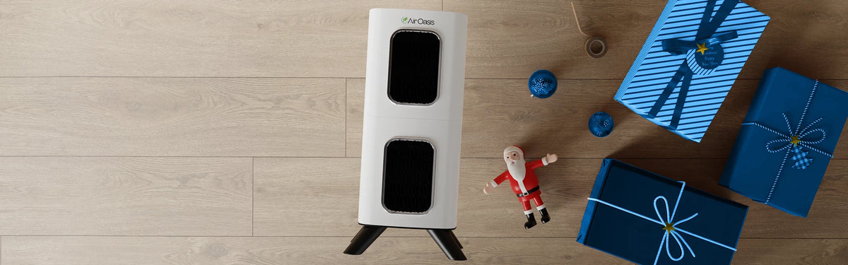 White air purifier with black screens on a wooden surface with blue gift boxes and a Santa Claus figure.